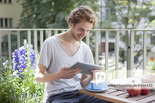 Lächelnder Mann mit digitalem Tablett auf der Veranda