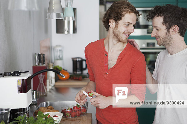 Affectionate gay couple looking at each other in kitchen