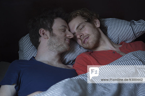 Entspanntes junges schwules Paar im Bett schlafend