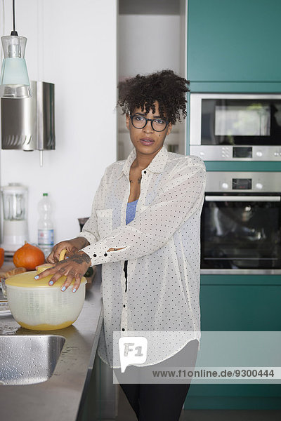 Portrait of young woman standing at kitchen counter