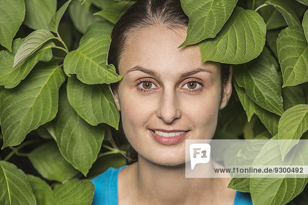 Porträt einer lächelnden Frau umgeben von Blättern