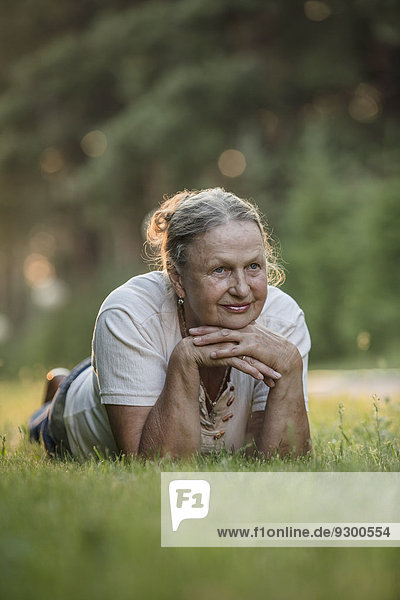 Nachdenkliche Seniorin im Park liegend