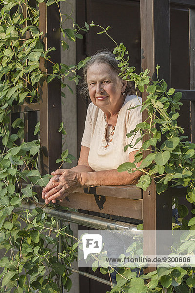 Porträt einer älteren Frau mit umklammerten Händen am Balkon