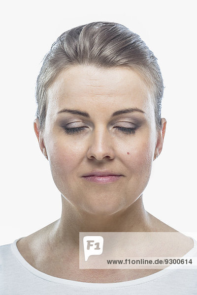 Mid adult woman with eyes closed against white background