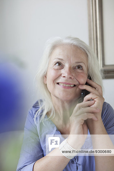 Glückliche Seniorenfrau  die zu Hause ans Handy geht