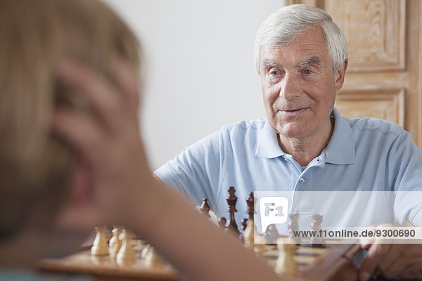 Senior Mann beim Schachspielen mit Enkel zu Hause