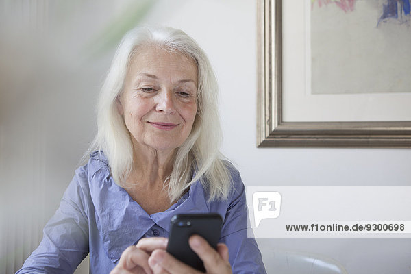 Senior Frau SMS über Smartphone zu Hause