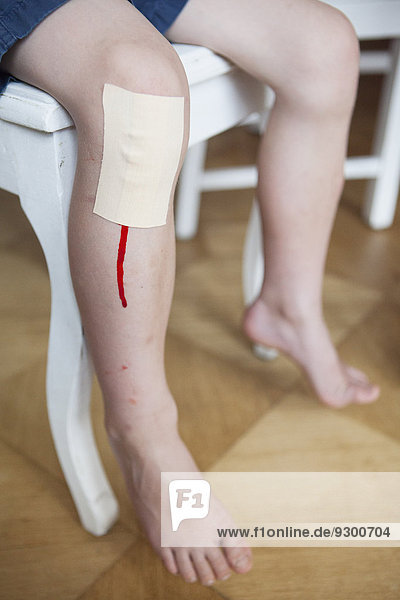 Niedriger Abschnitt des Jungen mit Blut  das aus dem Verband am Knie herausspritzt