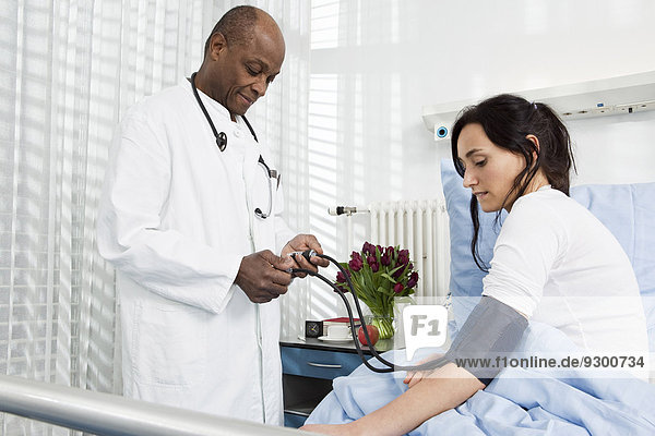 Ein Arzt  der den Blutdruck eines Patienten in einem Krankenhaus nimmt.