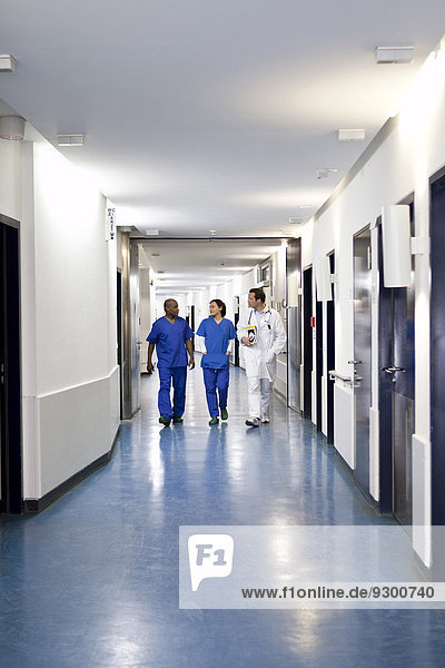 Drei Mediziner gehen gemeinsam einen Korridor in einem Krankenhaus entlang.