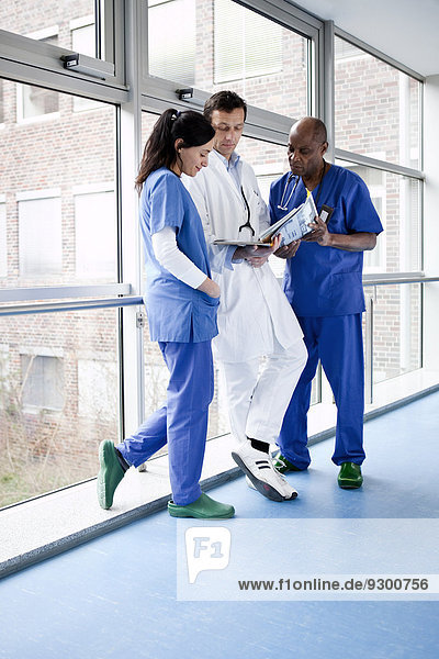Three medical professionals consulting over a medical file in a hospital