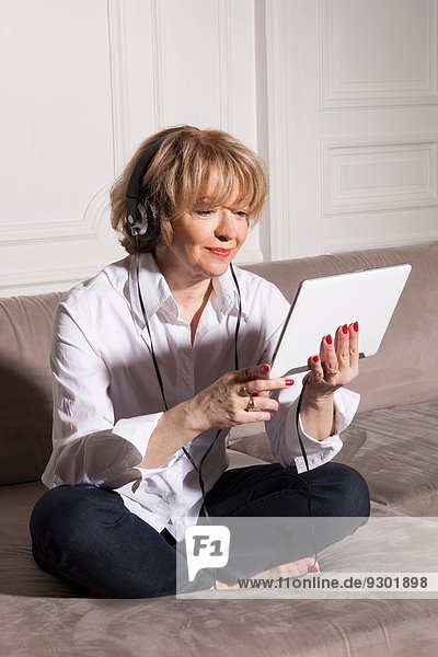 Frau mit digitalen Tablette auf Sofa