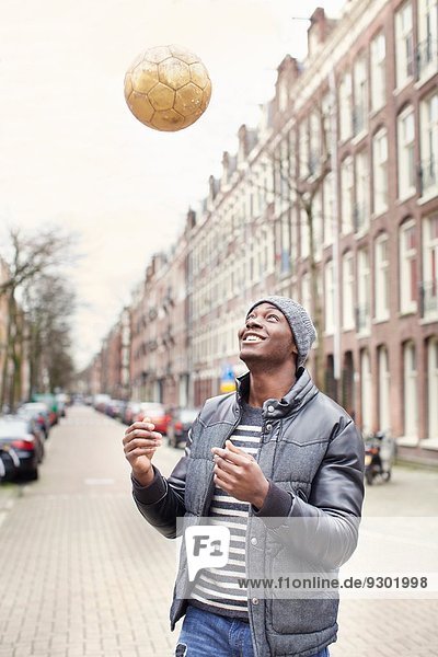 Young man on street throwing soccer ball  Amsterdam  Netherlands