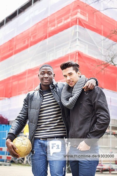 Porträt von zwei jungen Männern auf der Straße mit Fußball