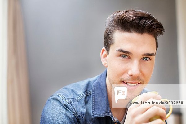 Porträt eines jungen Mannes beim Kaffeetrinken