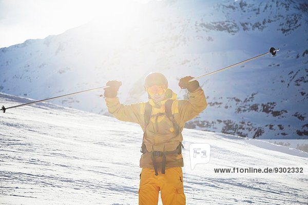 Mittlerer erwachsener Skifahrer  der Skistöcke hochhält  Österreich