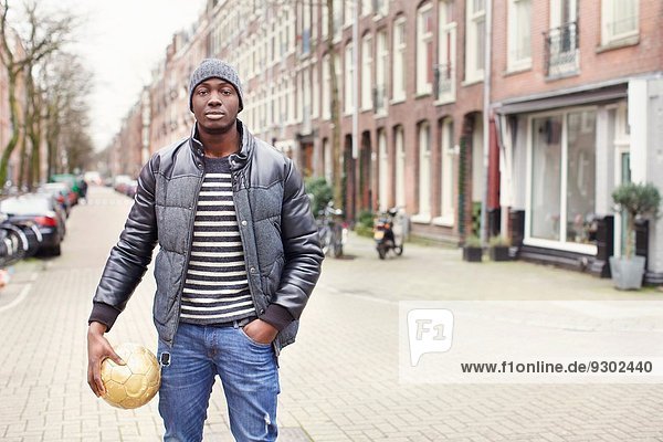 Porträt eines jungen Mannes auf der Straße mit Fußball  Amsterdam  Niederlande