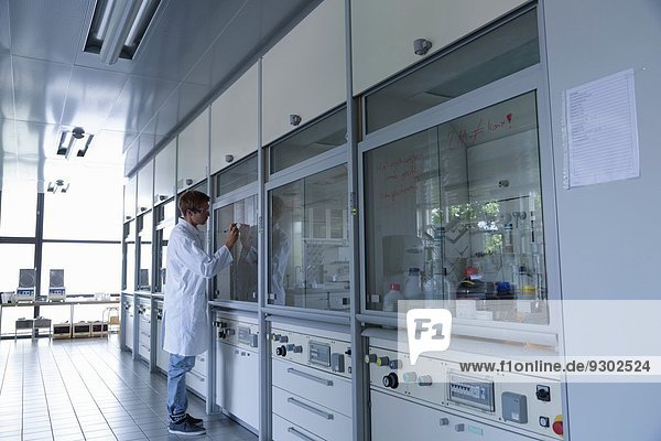 Junger Wissenschaftler schreibt am Laborabzugsfenster