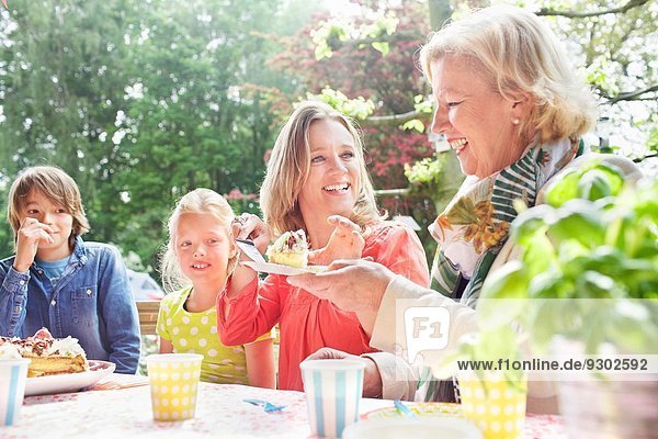 Mother serving birthday cake to family at birthday party