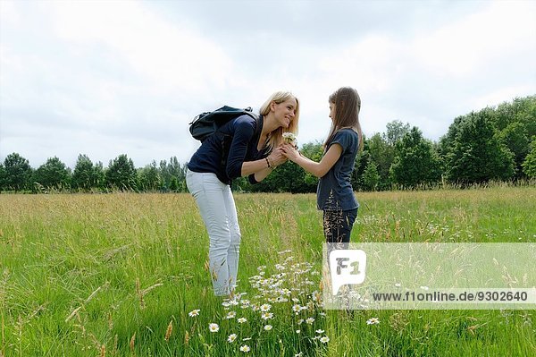 Mutter und Tochter riechen Wildblumen im Feld