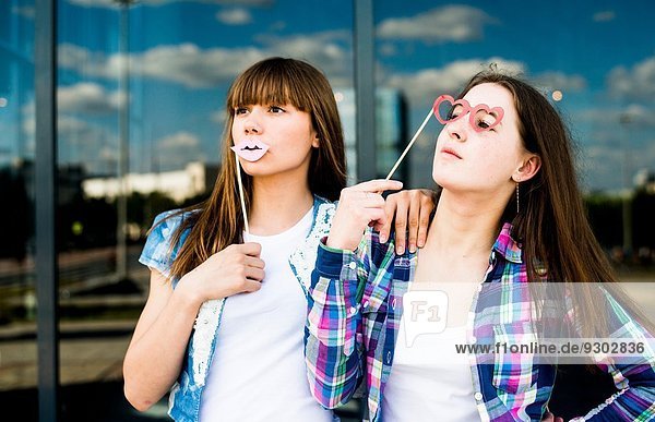 Zwei junge Frauen  die mit Lippen- und Brillenmasken aufblicken.