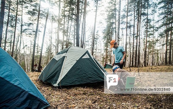 Two boys preparing tent for forest camping