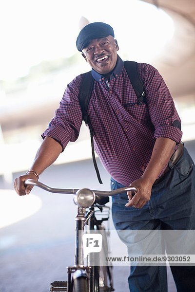 Älterer Mann schiebt Fahrrad durch die Stadtunterführung