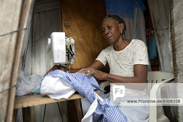 Seamstress working on a sewing machine in a hut  Camp Icare  camp for earthquake refugees  Fort National  Port-au-Prince  Haiti