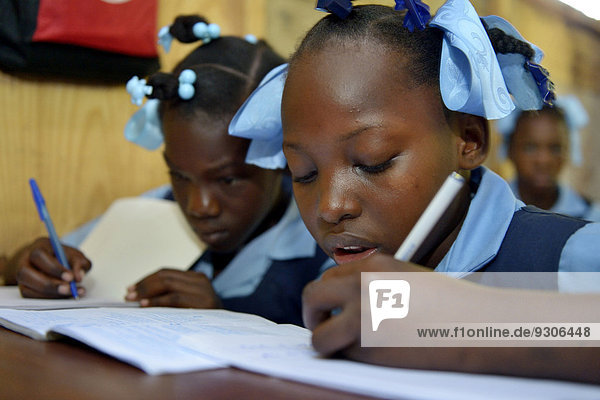 Zwei Mädchen schreiben in ein Heft  Schule für Erdbebenflüchtlinge  Fort National  Port-au-Prince  Haiti
