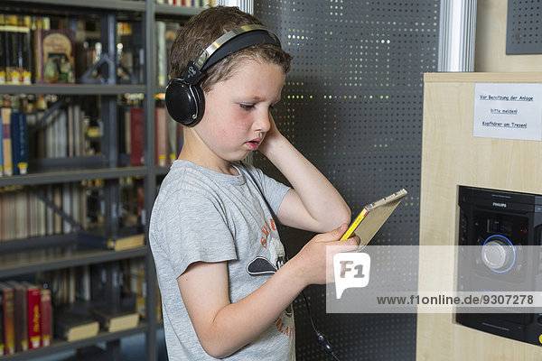Boy  7 years  listening to a CD with headphones  public library  Coswig  Saxony  Germany