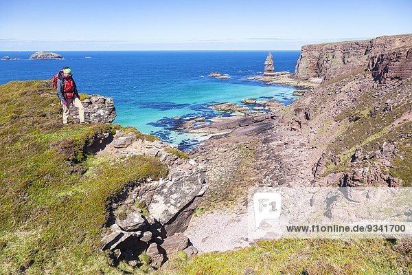Frau wandert durch Küstenlandschaft im Nordwesten Schottlands nahe der Sandwood Bay