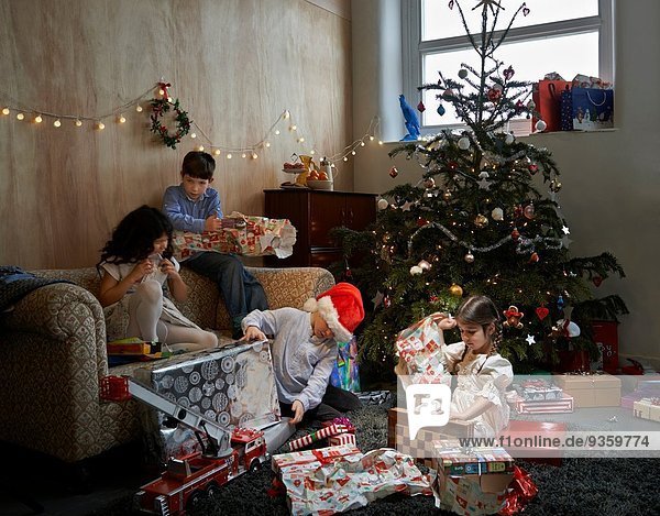 Sisters and brothers opening christmas gifts in sitting room