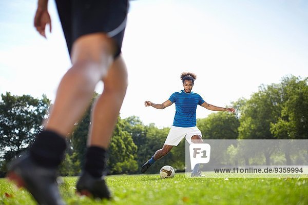 Junges Paar beim gemeinsamen Fussballspielen im Park