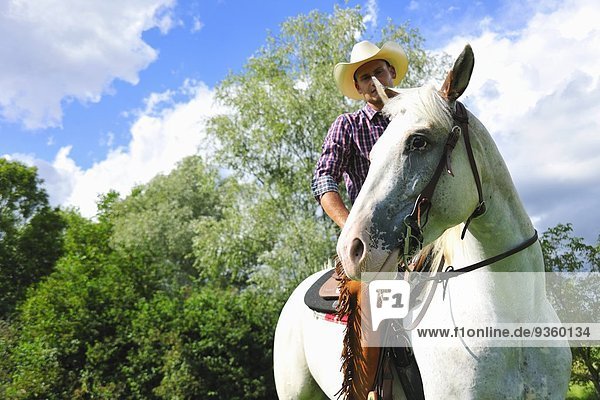 Flachwinkel-Porträt eines jungen Mannes in Cowboy-Ausrüstung zu Pferd