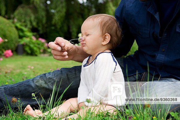Vater kitzelt Baby Töchter Nase mit Gras im Garten