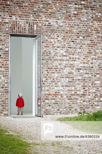 Junges Mädchen steht in der Tür in der Backsteinmauer