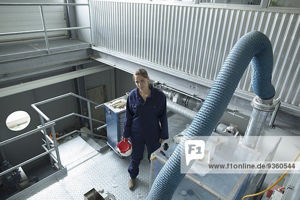High angle view of factory worker carrying plastic container