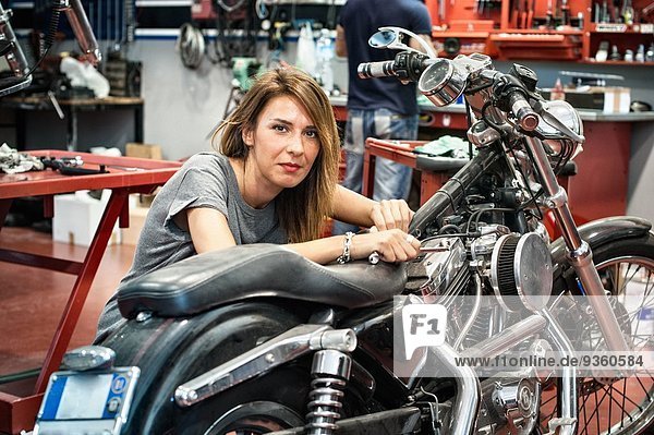 Porträt einer Mechanikerin in der Motorradwerkstatt