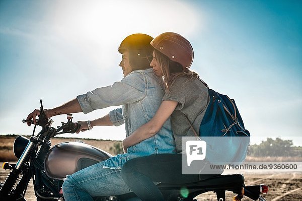 Mid adult couple motorcycling on arid plain  Cagliari  Sardinia  Italy