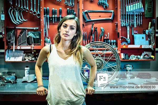 Porträt einer jungen Mechanikerin in der Motorradwerkstatt