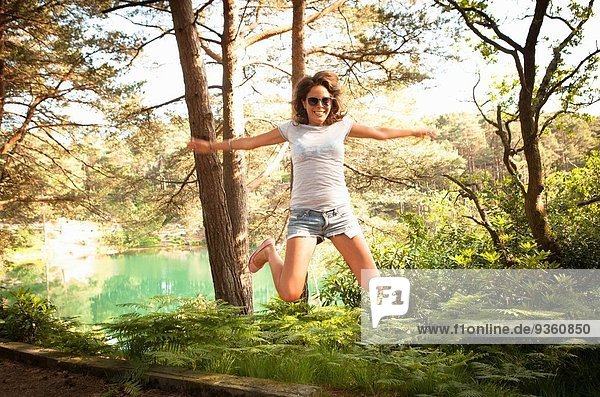 Mittlere erwachsene Frau springt in der Luft  Blue Pool  Wareham  Dorset  UK