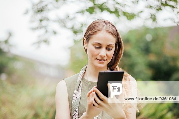 Junge Frau mit Touchscreen auf digitalem Tablett im Feld