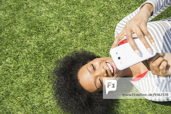 Handy liegend liegen liegt liegendes liegender liegende daliegen benutzen Frau amerikanisch Gras