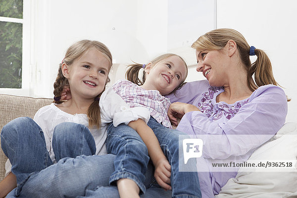 Germany  Munich  Mother with daughters (4-7) resting on sofa
