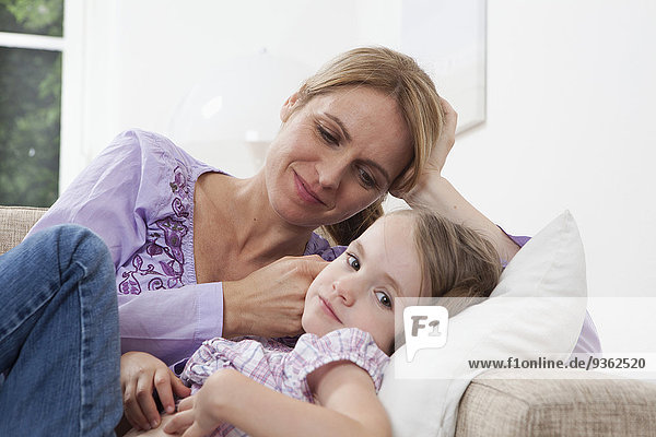 Germany  Munich  Mother with daughter (4-5) lying on sofa