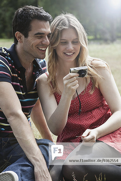 Germany  Berlin  Man and woman watching photo in digital camera  smiling