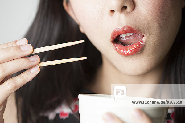 Asiatische Frau beim Essen mit Stäbchen