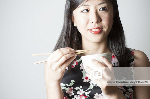 Porträt einer asiatischen Frau beim Essen mit Stäbchen