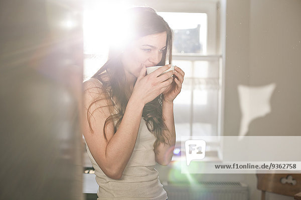Porträt einer jungen Frau beim Tee trinken am Morgen