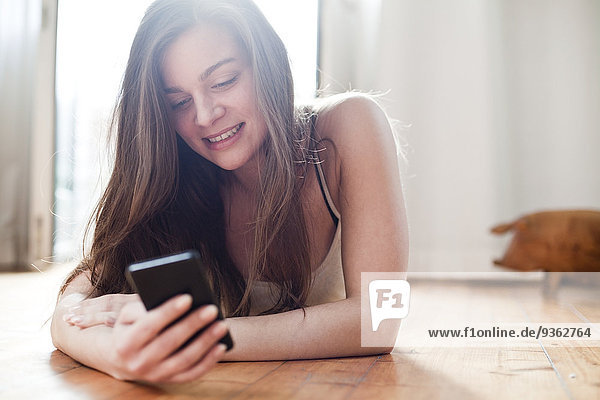 Portrait of smiling young woman using her smartphone at home